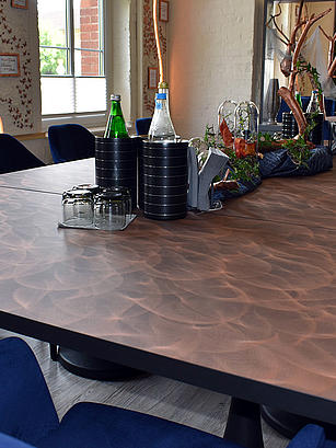 For the mix of copper, black and dark grey shades, a genuine metal was used for the first time on the table surfaces. Homapal supplied the “401/200 SRM” copper decor for this. 
